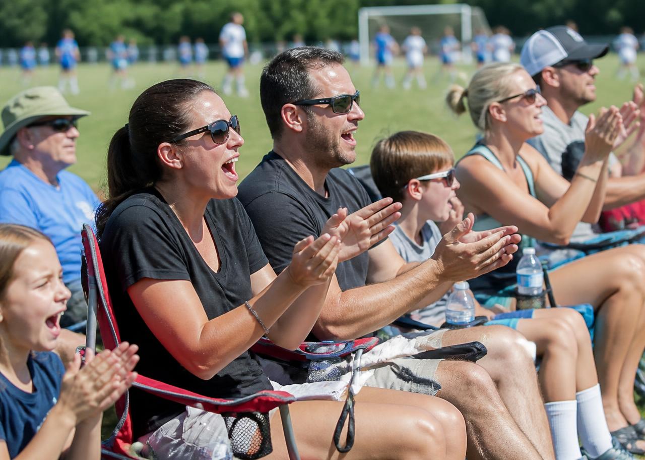 Parents cheering from the sideline of a youth soccer match